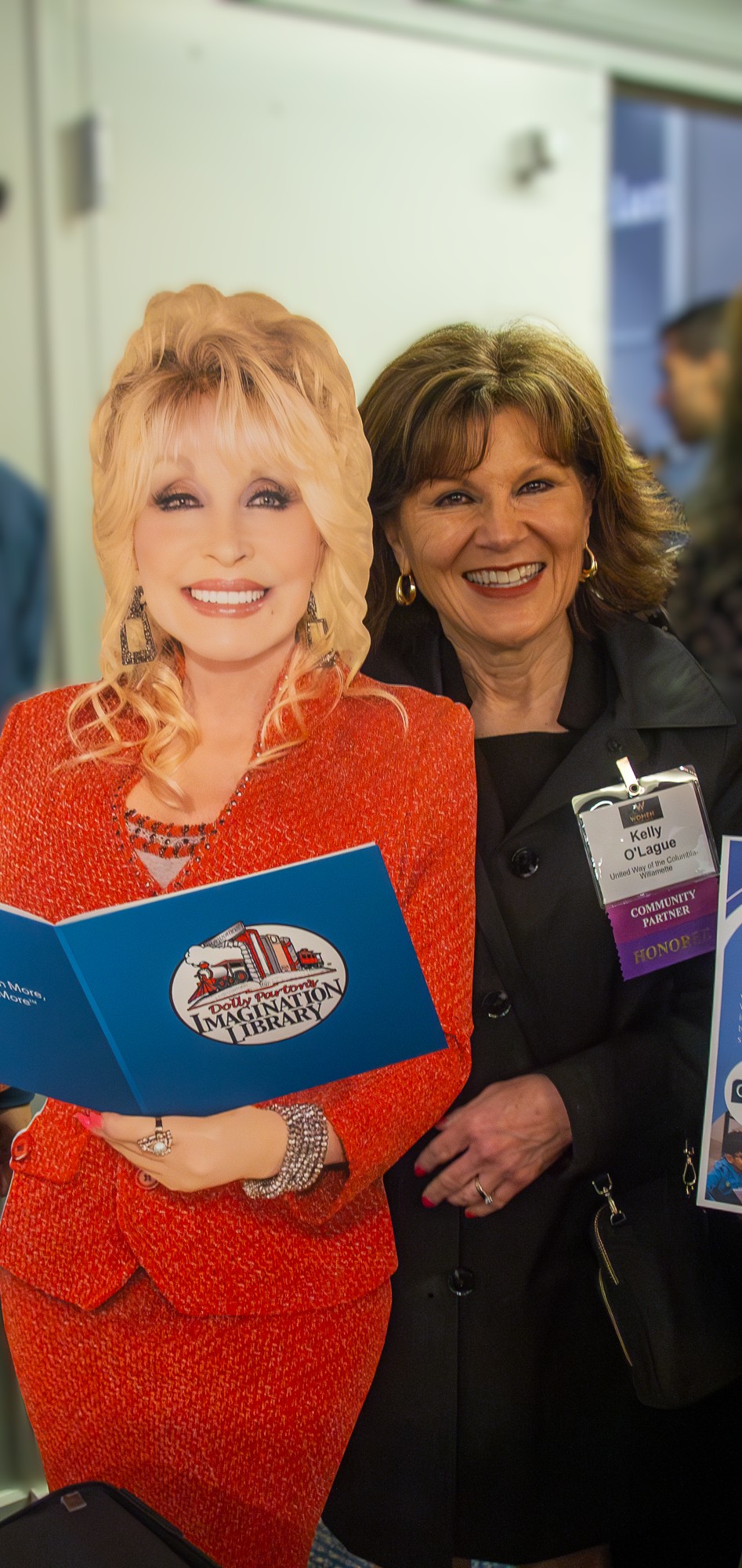 a woman stands with a cardboard cut out of Dolly Parton