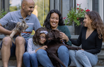 A photo of a family and a dog sitting on the steps of a house