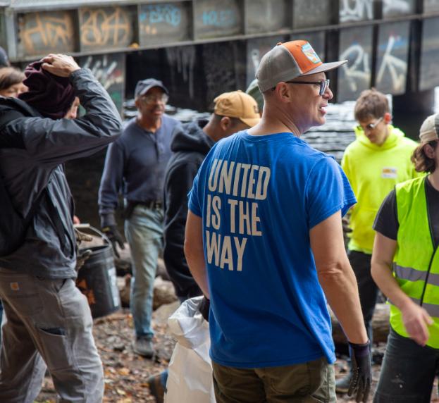 A man in a blue shirt saying United is the Way stands around a group of volunteers 